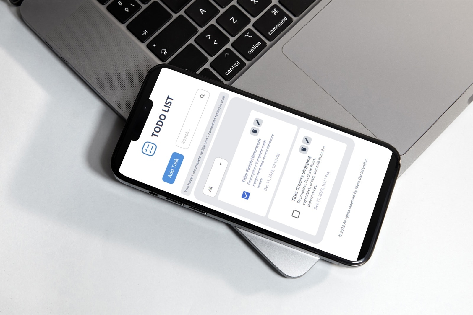 Todo list app on a phone resting on a laptop